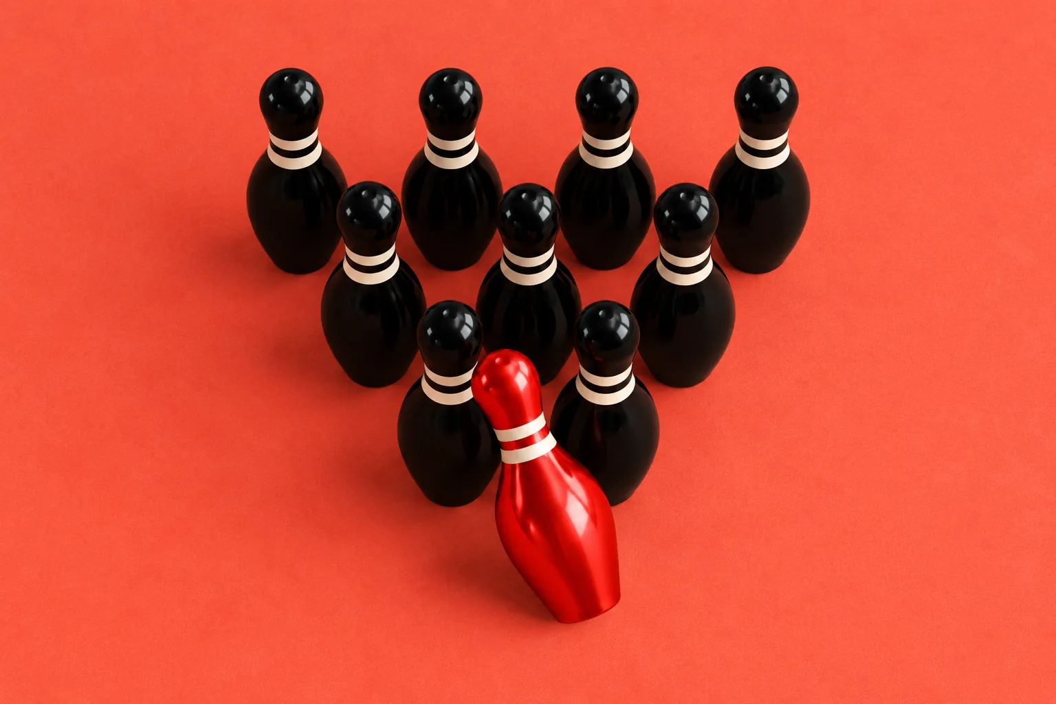 Ten black bowling pins in formation with a red head pin tipping at the front